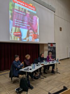 Moderatorin Nina Treu und die Podiumsteilnehmer*innen Heiko Rosenthal, Kristian Ronneburg und Heike Sudmann sitzen im Großen Hörsaal des Sportcampus der Uni Leipzig