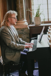 Robin sitz an einem schwarzen Klavier. Er musiziert und singt.